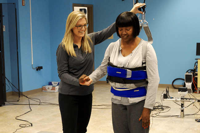 therapist assists stroke survivor with walking harness