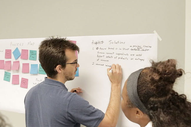 Student working on a process plan on a white board