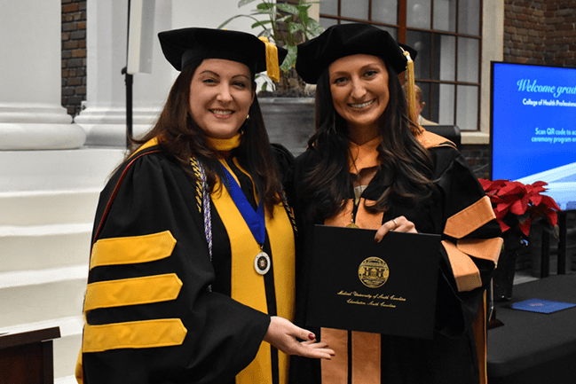 two women pose at a graduation