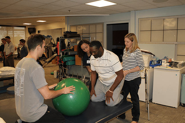 PT students help a patient with physical therapy exercise