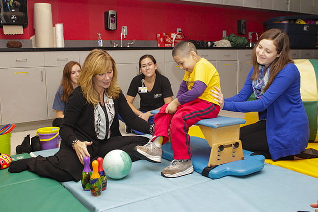 Four women providing occupational therapy to a child