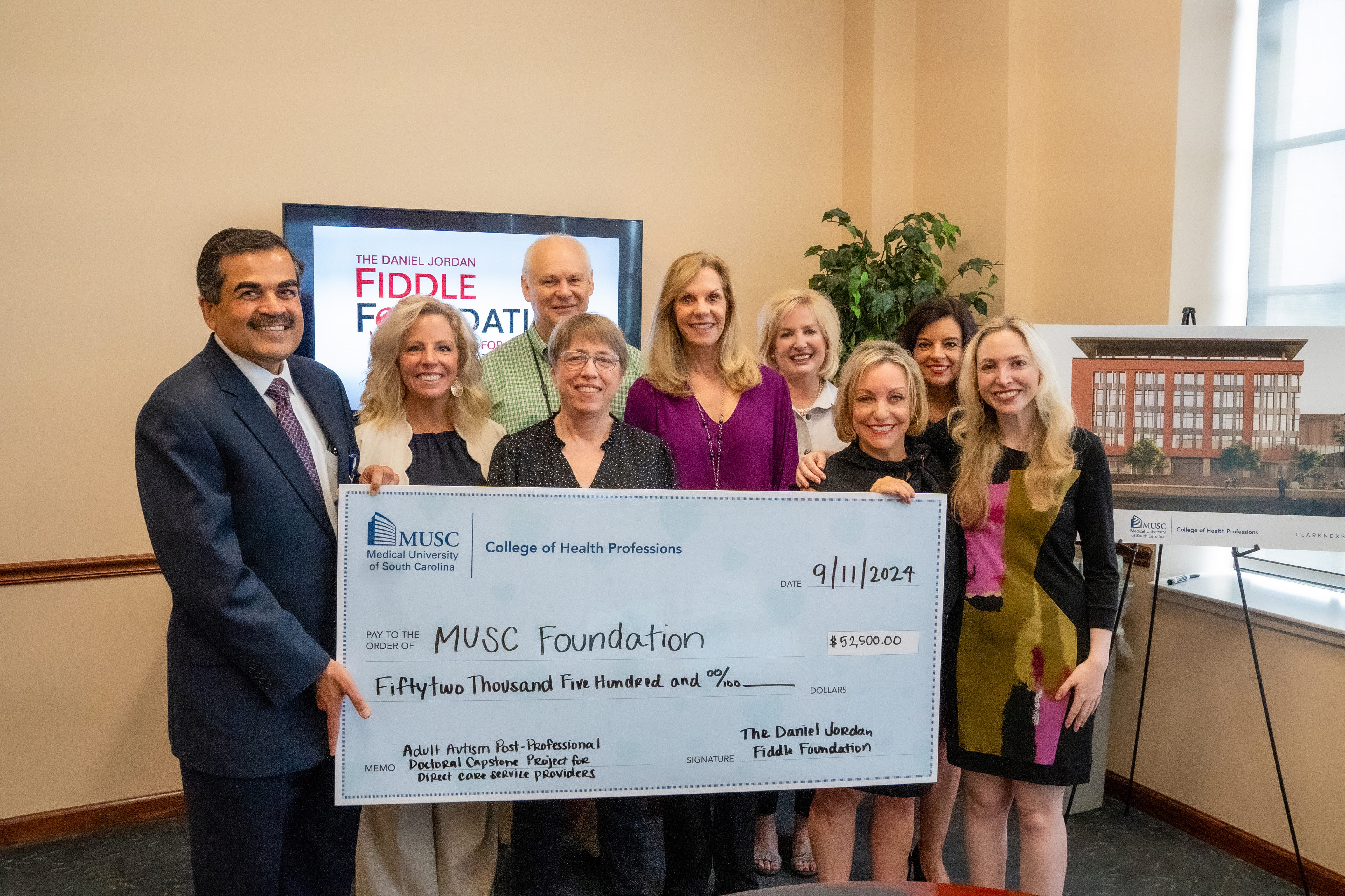 CHP leaders and DJFF leaders hold a large check in a conference room. The DJFF logo is on a screen in the background 