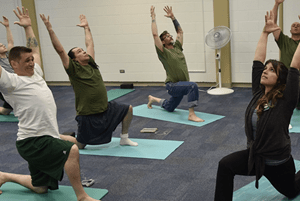 OT alumnus Kaelyn Rogers practicing yoga with male inmates