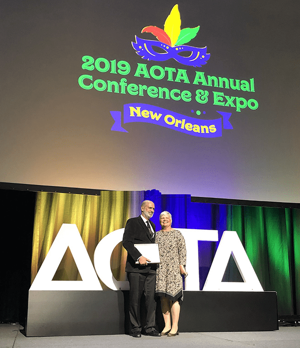 Craig Velozo on stage at the 2019 AOTA Conference accepting his Slagle Lectureship award.