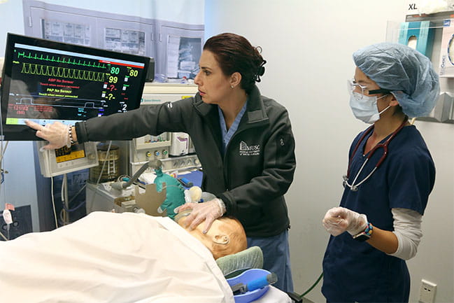 Anesthesia for nurses professor teaching student how to use equipment.
