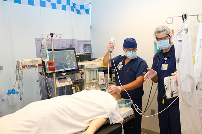 Two anesthesia for nurses students practicing in the simulation lab.
