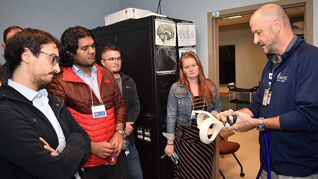 Instructor demonstrates transcranial magnetic stimulation coil to workshop attendees